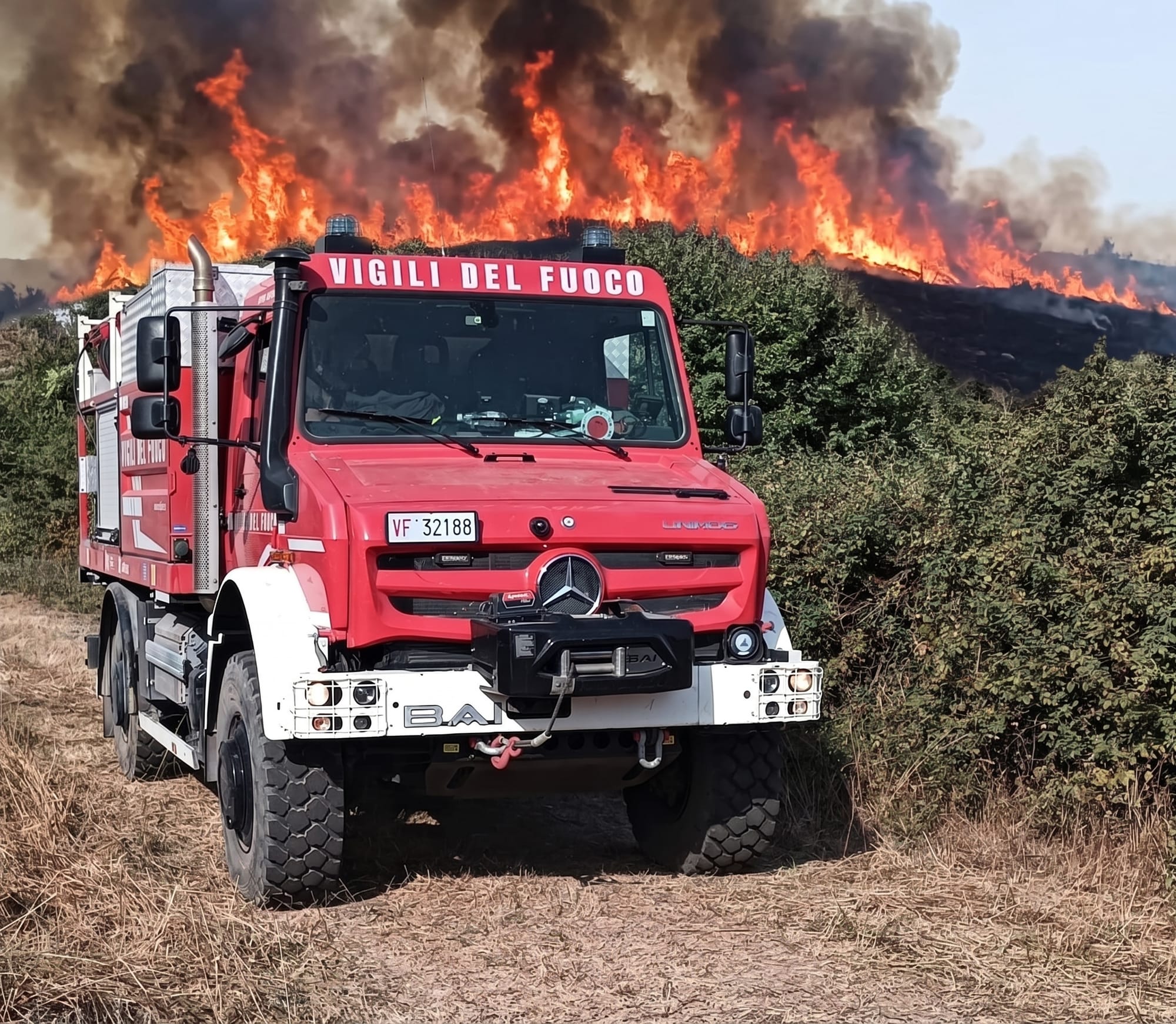 Mezzo dei Vigili del Fuoco davanti a un vasto incendio